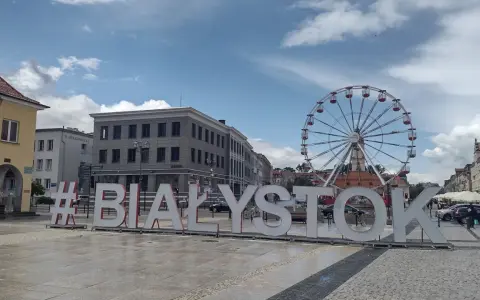 #Białystok - wielki napis zaprasza do odkrywania atrakcji miasta, w tle koło widokowe i zabytkowa zabudowa.