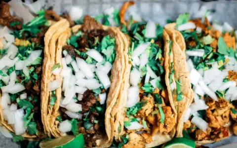 Fünf köstliche Tacos mit Rindfleisch und Hähnchen, garniert mit Zwiebeln und Koriander. Perfekt für einen Taco-Abend!