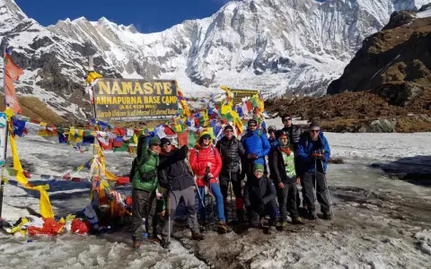 Grupa turystów na tle Annapurny podczas trekking w Nepalu. W tle majestatyczne, ośnieżone szczyty i kolorowe flagi modlitewne.