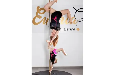 Dwie tancerki, dorosła i dziecko, wykonują akrobacje na słupie. To dowód, że pole dance dla dzieci to świetna zabawa i aktywność.