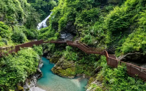 Sentiero panoramico tra gole e cascate, un esempio di posti strani da visitare in Italia, con passerelle in metallo che si snodano tra la vegetazione lussureggiante.