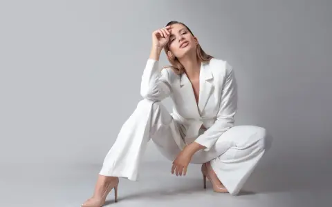 Elegancka kobieta w białym garniturze i cielistych szpilkach. Idealne buty do białego garnituru podkreślają stylizację.