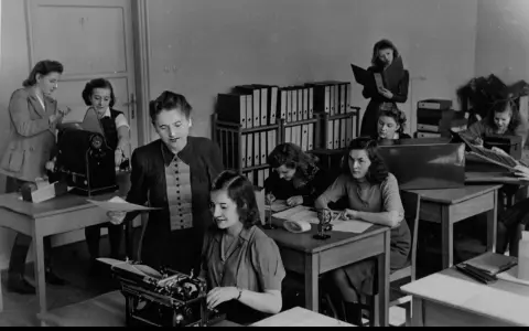 Kobiety pracujące w biurze, jedna przy maszynie do pisania, inne nad dokumentami. To właśnie tajne komplety, czyli tajne nauczanie, które odbywało się w ukryciu.