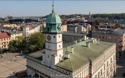 Widok na rynek na Kazimierzu w Krakowie z wieżą ratuszową i zielonymi dachami.