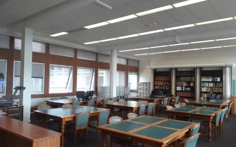 Salle de lecture avec tables, chaises et étagères de livres.