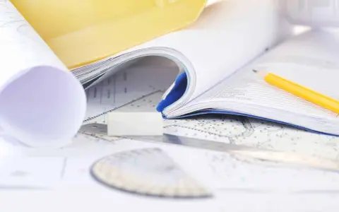 Plany, żółty ołówek i gumka na mapach. Projektowanie przestrzeni, obliczanie powierzchni użytkowej.