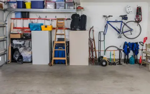 Garage med cykel, stegar, förvaringslådor och en liten fönsterlucka för ventilation.
