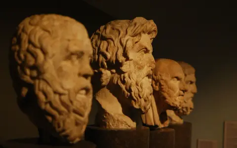 Bustos de mármol de filósofos de la edad antigua Grecia, con barbas y miradas serias, alineados en un museo.
