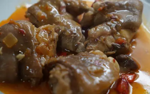 Manitas de cerdo en salsa, un plato de comida típica de Valladolid, con trozos de pimiento y cebolla.