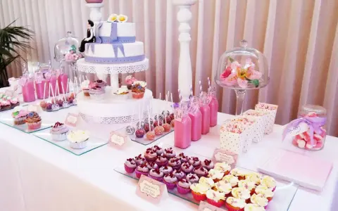 Mesa dulce para 50 cumpleaños con pastel de dos pisos, cupcakes, cake pops, bebidas rosas y palomitas.