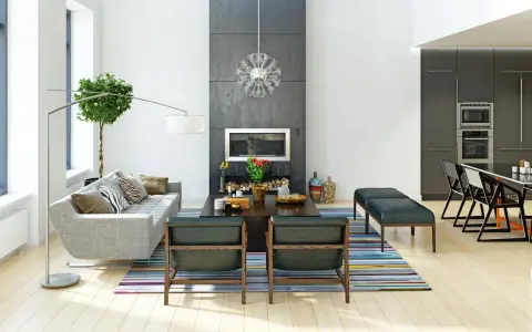 Nowoczesne wnętrza: szara sofa, kominek, designerskie krzesła i kuchnia. Różnorodne style wnętrz w jednym, przestronnym salonie.
