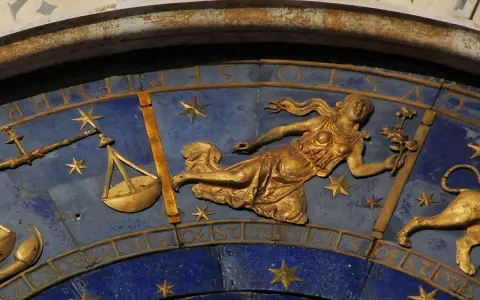 Złota postać z kwiatami, symbol znaku zodiaku Panna, obok wagi i lwa. 24.08 znak zodiaku.