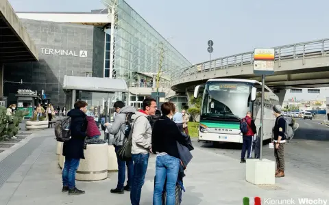 Ludzie czekają na autobus przed Terminalem A na lotnisku w Katanii.