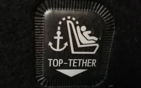 Symbol mocowania fotelika ISOFIX z kotwicą i dzieckiem. To jest oznaczenie TOP TETHER.
