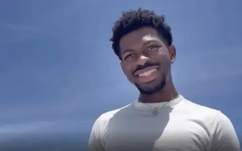 Lil Nas X, uśmiechnięty na tle błękitnego nieba. Czy Lil Nas X jest gejem? To pytanie często pojawia się w dyskusjach o jego życiu.