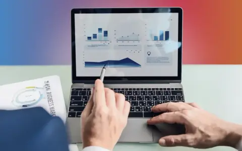 Ręce analizują wykresy na laptopie, przygotowując materiały do seo bloga.