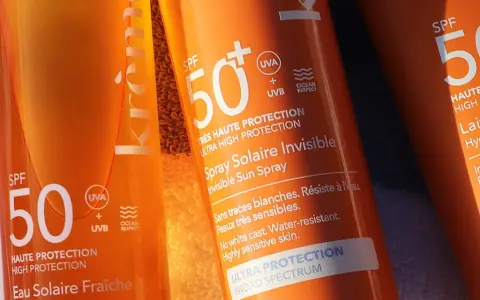 Trois tubes de crème solaire, tous avec SPF 50, prêts pour la protection solaire. L'un est un spray invisible, l'autre un lait hydratant.