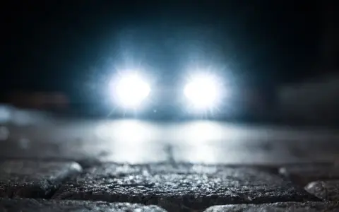 Jasne światła samochodu przebijają mrok. Kiedy jakie światła w aucie są kluczowe dla bezpieczeństwa na mokrej nawierzchni.