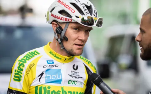 Radsportler mit Helm und Mikrofon, bereit für ein Interview nach einem harten Rennen, vielleicht dem Race Across America.