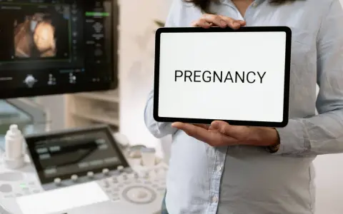Wczesna ciąża, 2 tydzień. USG pokazuje zarodek, a na tablecie widnieje napis "PREGNANCY".