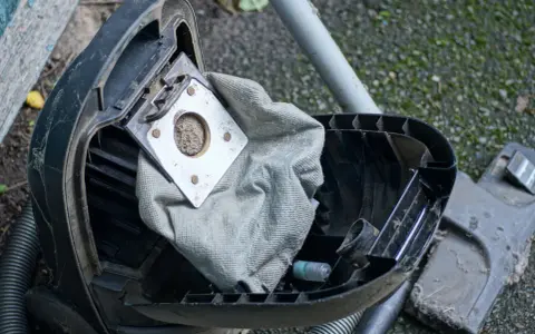 Ein staubsauger beutel wechseln ist nötig. Der alte, volle Beutel liegt offen, bereit für den Austausch.