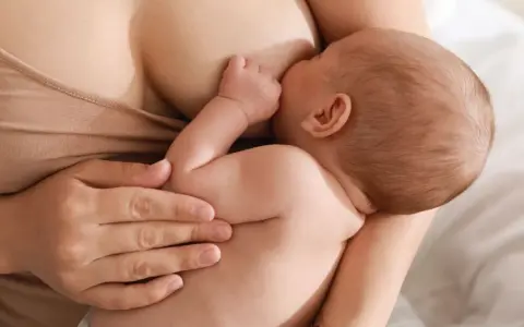 Un neonato si nutre al seno, ricevendo il prezioso colostro, un dono naturale per la sua crescita.