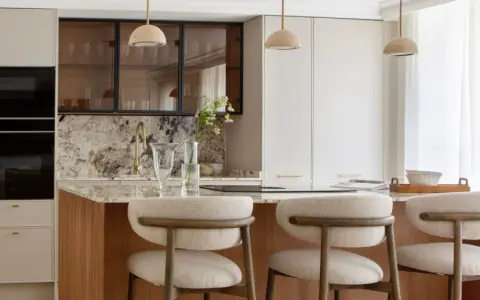 Cocina moderna con isla central, taburetes y electrodomésticos integrados. Un diseño atemporal que combina funcionalidad y elegancia.
