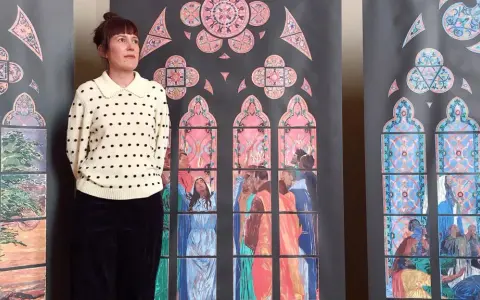 Une femme pose devant des vitraux stylisés, évoquant les vitraux de Notre Dame. Les scènes colorées représentent des figures humaines et des motifs floraux.