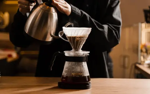 Person gießt heißes Wasser über Kaffeepulver in einem Filter. Die richtige filterkaffee temperatur ist entscheidend für den Geschmack.