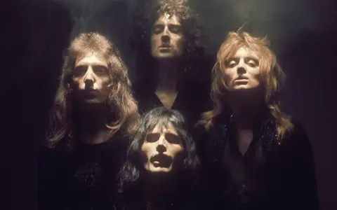 Czterech członków zespołu Queen w mrocznym klimacie, jakby przygotowujących się do wykonania "Bohemian Rhapsody". Ich spojrzenia sugerują głęboką interpretację.