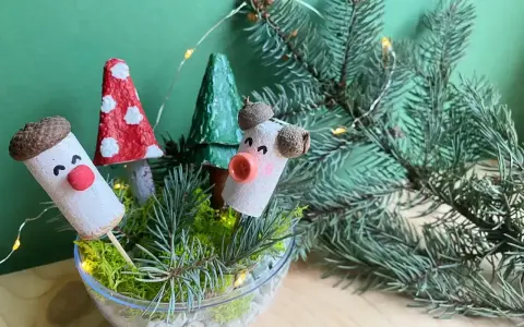 Uroczy stroik DIY z korkowych ludzików, grzybków i choinek w szklanej misie, ozdobiony gałązkami świerku i lampkami.
