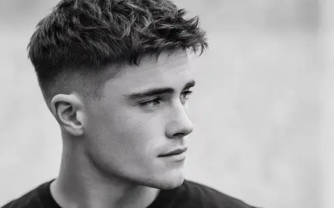 Perfil de hombre joven con corte de pelo moderno, un degradado rasurado impecable que se funde con la piel.
