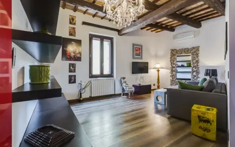 Soggiorno con travi a vista, lampadario di cristallo e un tocco di stile rustico.