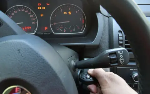 Ręka wkłada kluczyk do stacyjki, by dokonać kasowania błędów w samochodzie. Na desce rozdzielczej świecą się kontrolki.