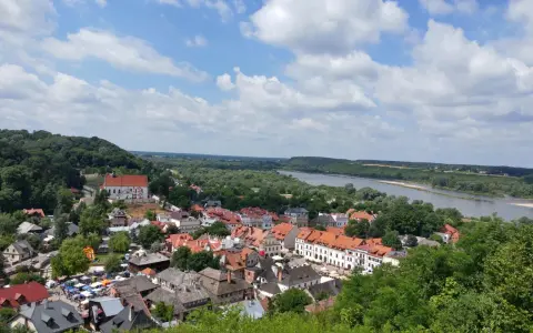 Widok na miasteczko z rzeką i lasami. W oddali widać wzgórze z krzyżami.