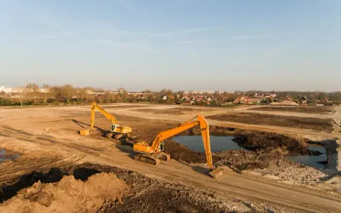 Excavadoras trabajan en un sitio de remediación de suelos, moviendo tierra y agua para restaurar el terreno.
