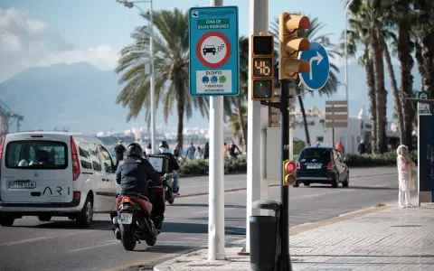 Señal de zona de bajas emisiones en Vigo. Coches y motos circulan bajo palmeras.