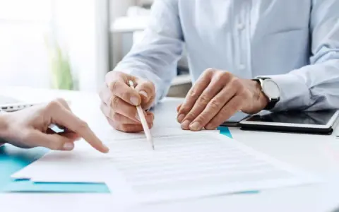 Due mani esaminano un documento, una indica un punto mentre l'altra tiene una matita, forse per la dichiarazione di inizio attività.