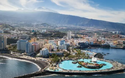 Puerto de la Cruz atrakcje: Lago Martianez, baseny z wodą morską, plaża, miasto i wulkan Teide w tle.