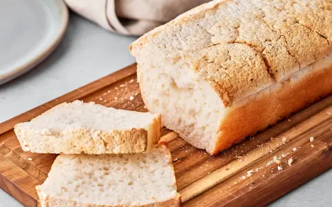 Ein Laib japanisches Reisbrot, aufgeschnitten auf einem Holzbrett. Dieses Rezept für japanisches Reisbrot ist perfekt für alle, die glutenfreies Brot lieben.