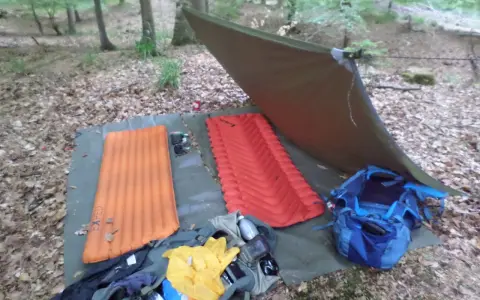 Zwei Isomatten, ein Tarp und Rucksäcke liegen bereit, um unter freiem Himmel zu schlafen.