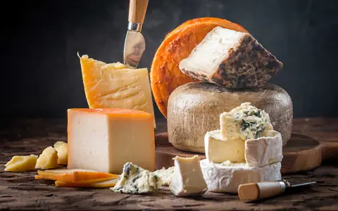Kuski najlepsze sery: parmezan, pleśniowy, camembert i inne, ułożone na drewnianej desce.
