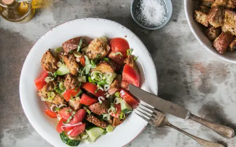 Ein erfrischender toskanischer Brotsalat mit Tomaten, Gurken und knusprigen Brotwürfeln, garniert mit frischen Kräutern.