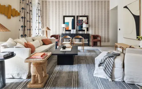 Elegante sala de estar con sofás blancos, mesa de centro negra y alfombras a rayas que complementan la decoración de la casa.