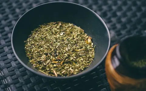 Suszone liście yerba mate w czarnej miseczce, gotowe do zaparzenia. To naturalny napój pobudzający.