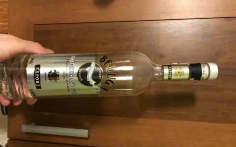 Butelka wódki Beluga Export, z etykietą "Noble Russian Vodka", leży na drewnianym blacie.