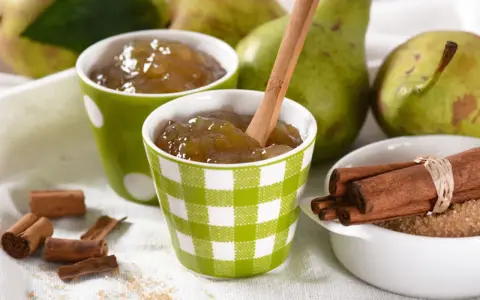 Due tazze con **marmellata di pere** fatta in casa, pere fresche, cannella e zucchero di canna.