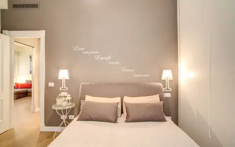 Camere da letto belle con citazione "Live, Laugh, Love" sulla parete. Letto accogliente con cuscini e lampade moderne.