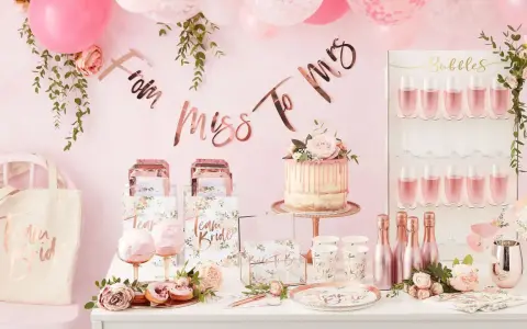 Uroczy wystrój na wieczór panieński: tort, balony, napisy "From Miss To Mrs", torby "Team Bride" i kieliszki z różowym napojem. Idealne pomysły, co robic na panieńskim!