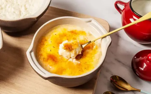 Delicioso arroz con leche asturiano con una capa crujiente de caramelo. Una cuchara dorada levanta una porción cremosa.
